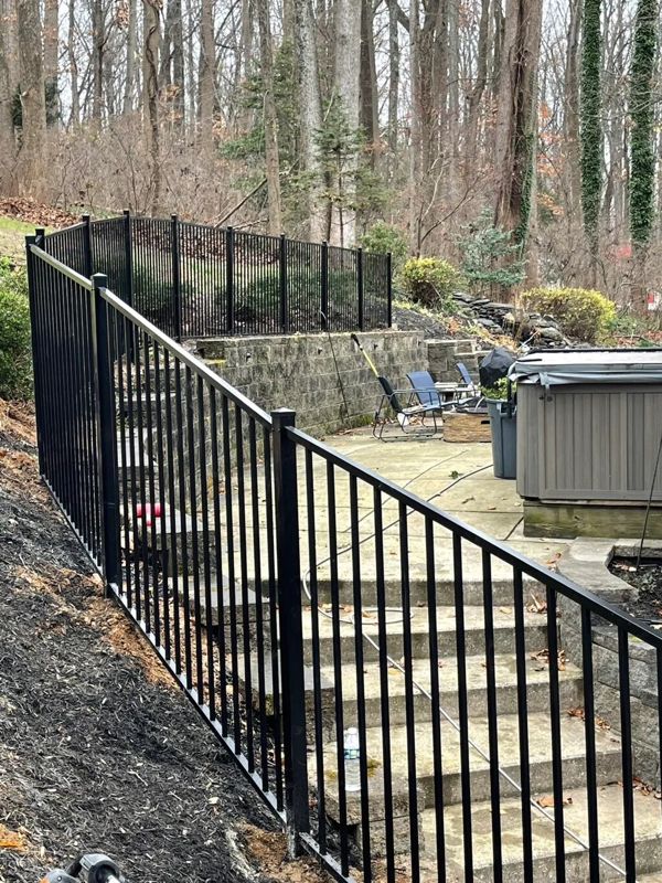 Aluminum fencing along stone steps and a hot tub patio