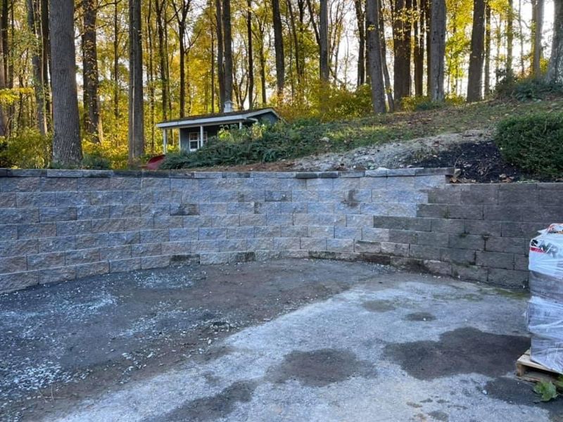 Tall curved block wall holding back a wooded slope