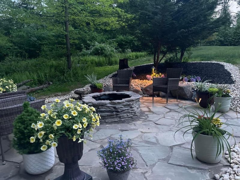Natural flagstone patio with a stone fire pit, seating and planters