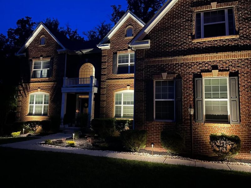 Path lights and home uplighting on a brick colonial
