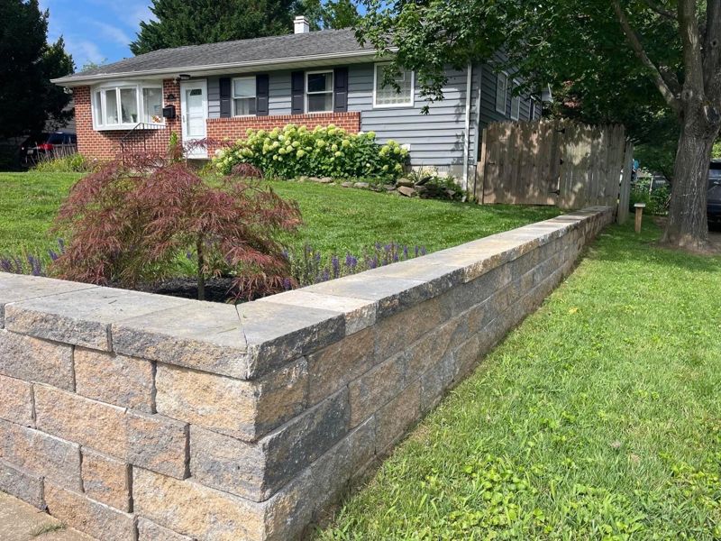 Block retaining wall with a capped top and new plantings